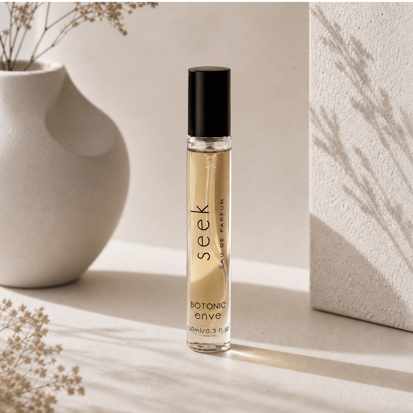 Perfume bottle labeled 'seek' on a light surface with a vase and dried flowers in the background.