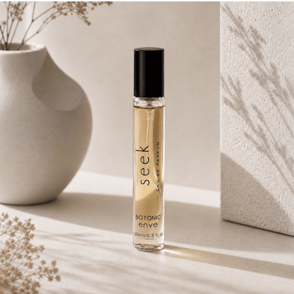 Perfume bottle labeled 'seek' on a light surface with a vase and dried flowers in the background.